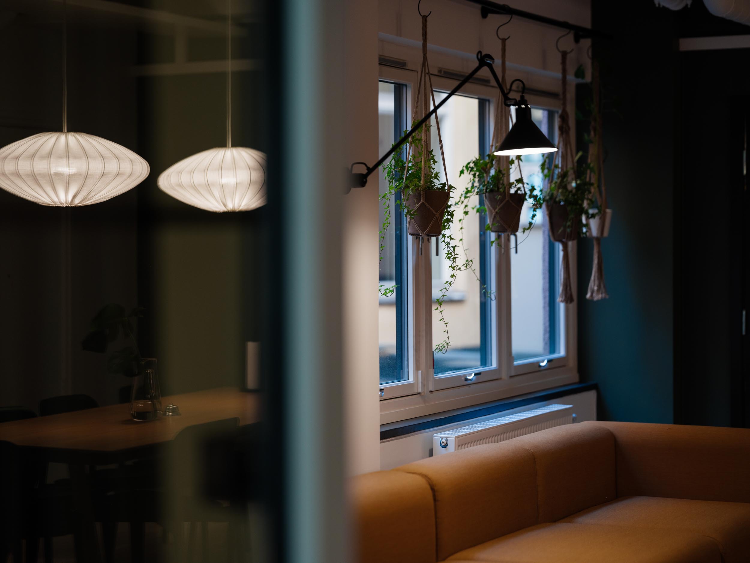 Pendellamper, grønne planter og en oransje sofa på Behalf-kontoret