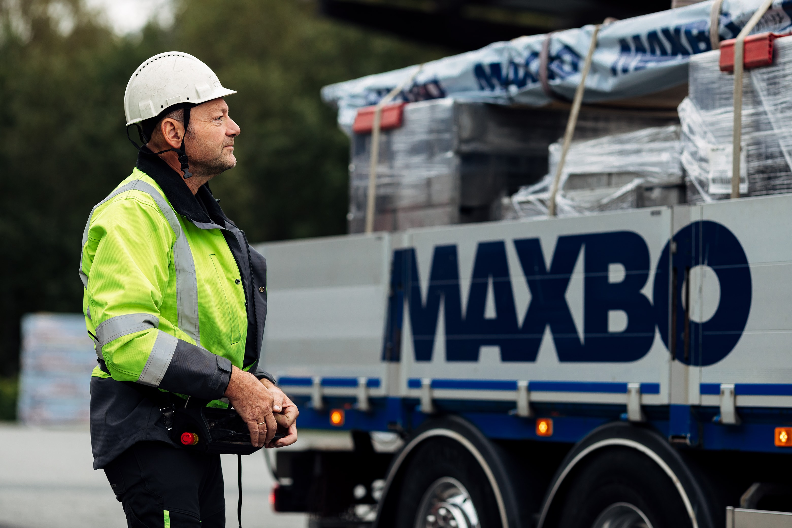 En Maxbo-ansatt foran en lastebil med byggevarer
